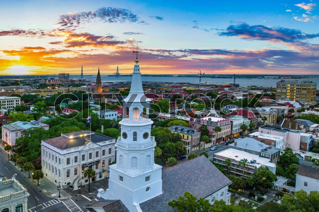 Aerial view of Charleston SC during a vibrant sunset, featuring historic downtown and church.
