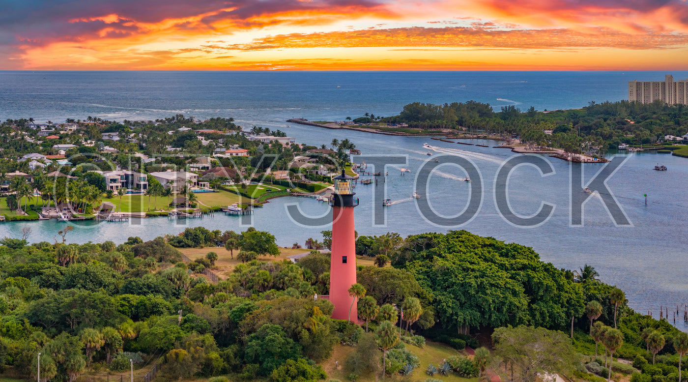 Lush waterfront landscape with red Jupiter Lighthouse during sunset