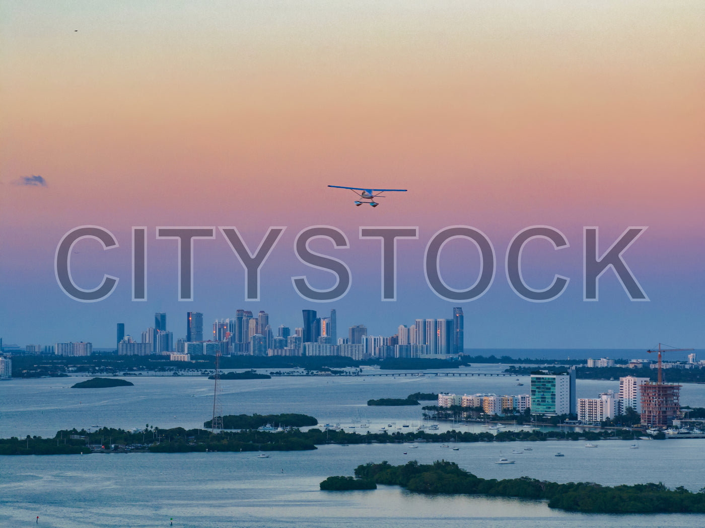 Miami skyline and Biscayne Bay view during sunset with airplane
