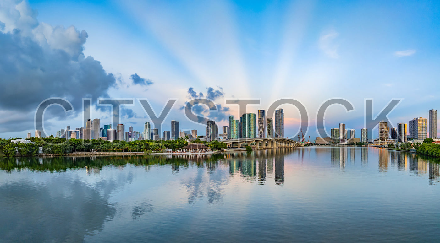 Sunrise illuminating Miami skyline with reflective cloud patterns