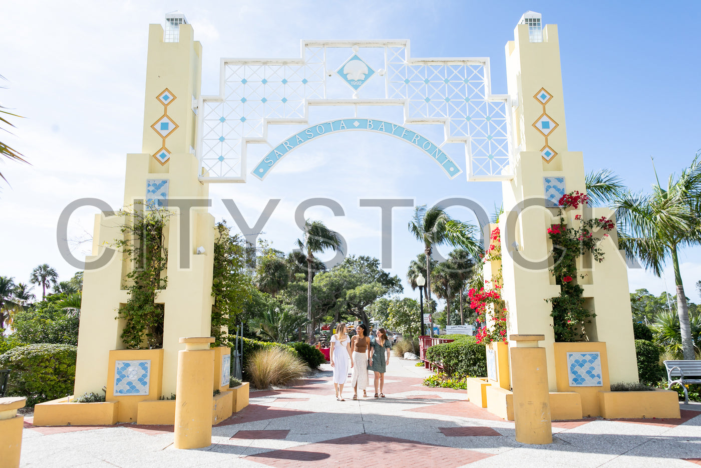 Group of friends walking under Sarasota Bayfront gate on sunny day