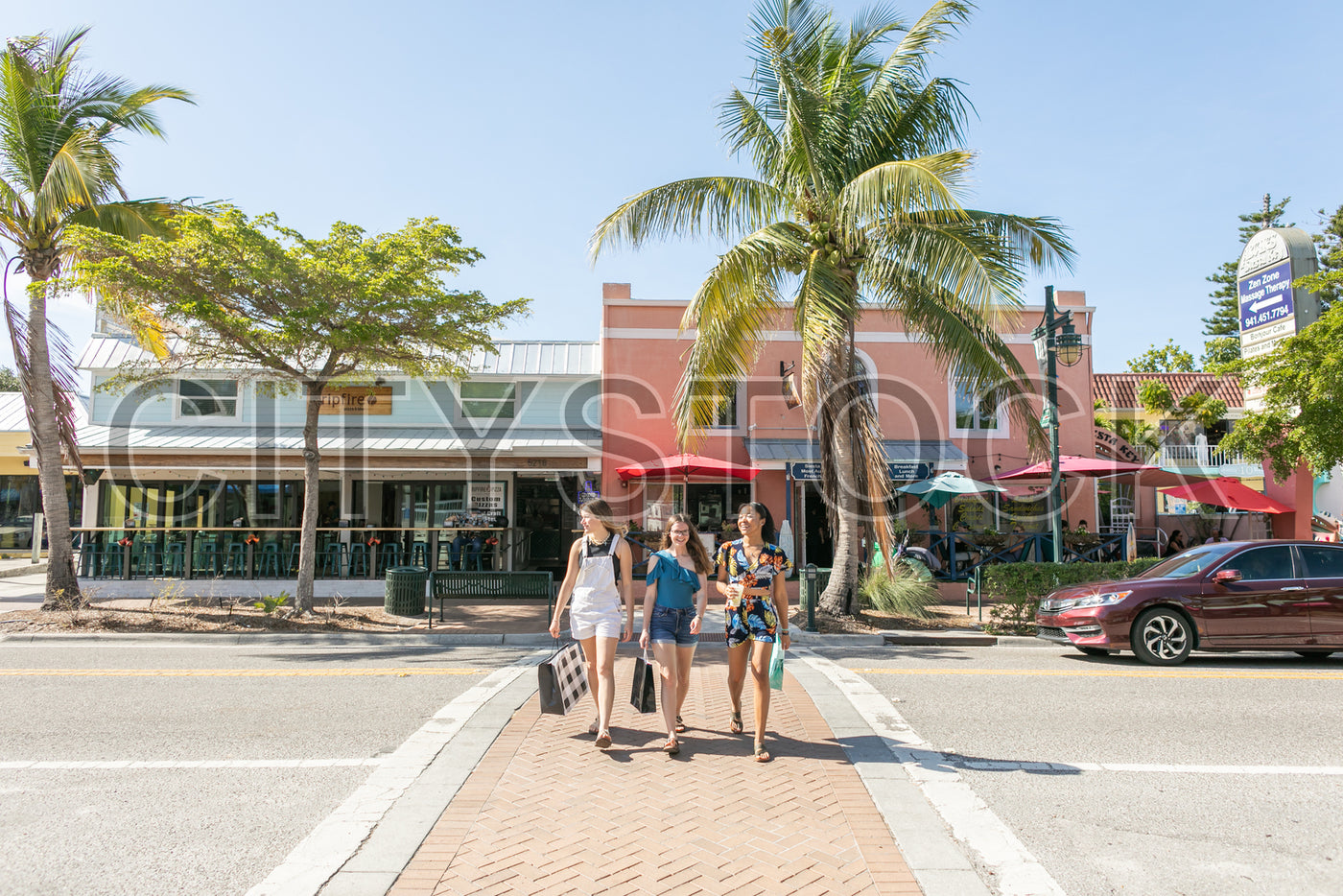 Friends walking on a sunny Sarasota street with palm trees