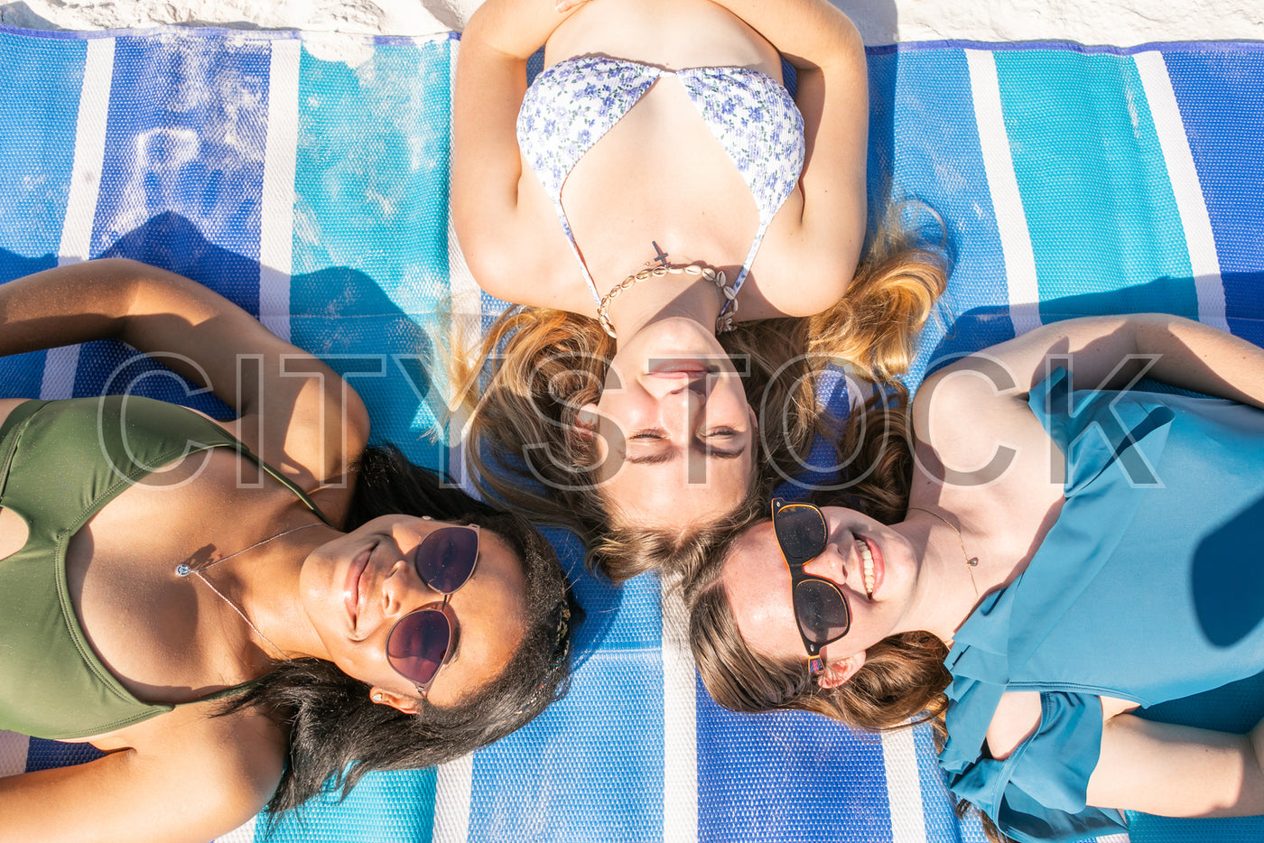 Three women lying on beach towels, enjoying the summer sun in Sarasota