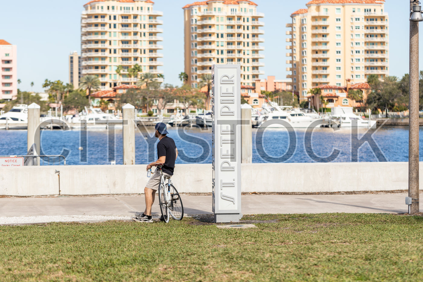 Cyclist pausing by St. Pete Pier with waterfront backdrop