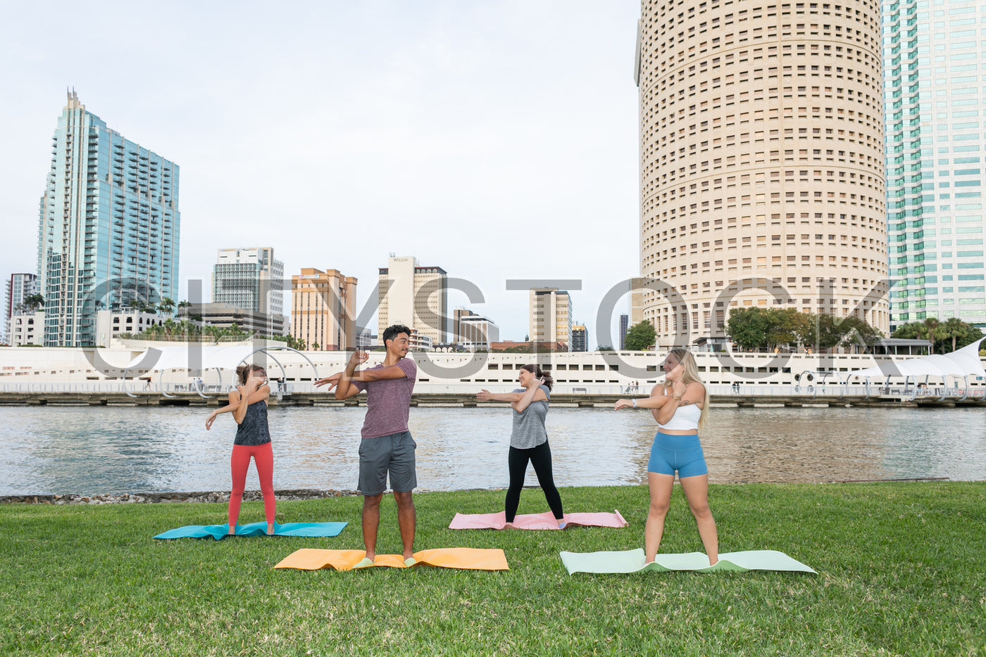 Group practicing yoga in urban Tampa, skyscrapers backdrop