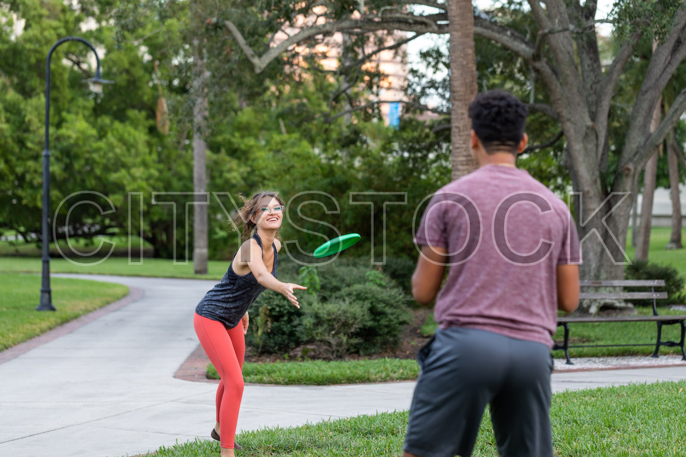Young woman catching frisbee in Tampa park, sporting vibrant casual wear