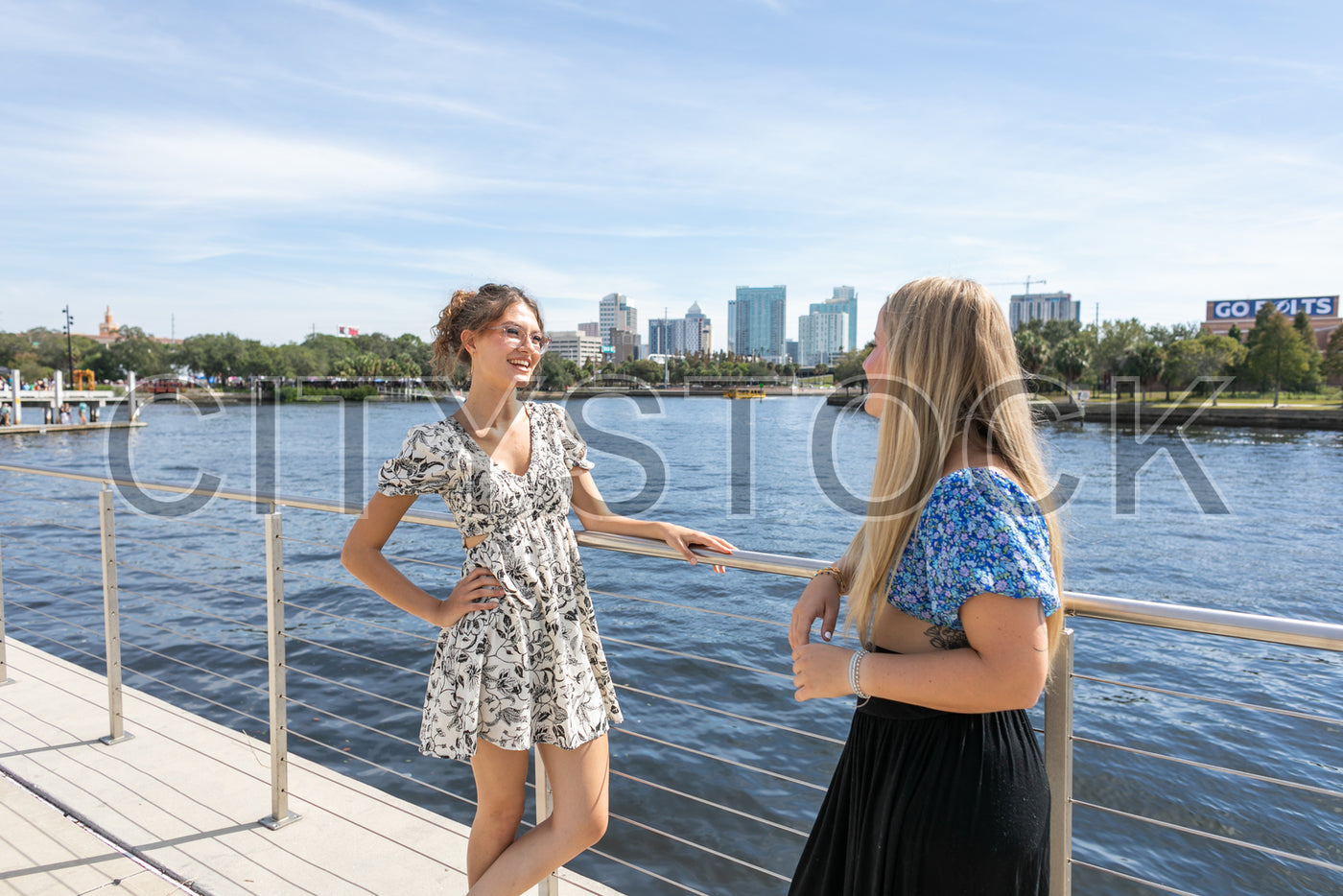 Two women chatting on Tampa Riverwalk with city skyline in background