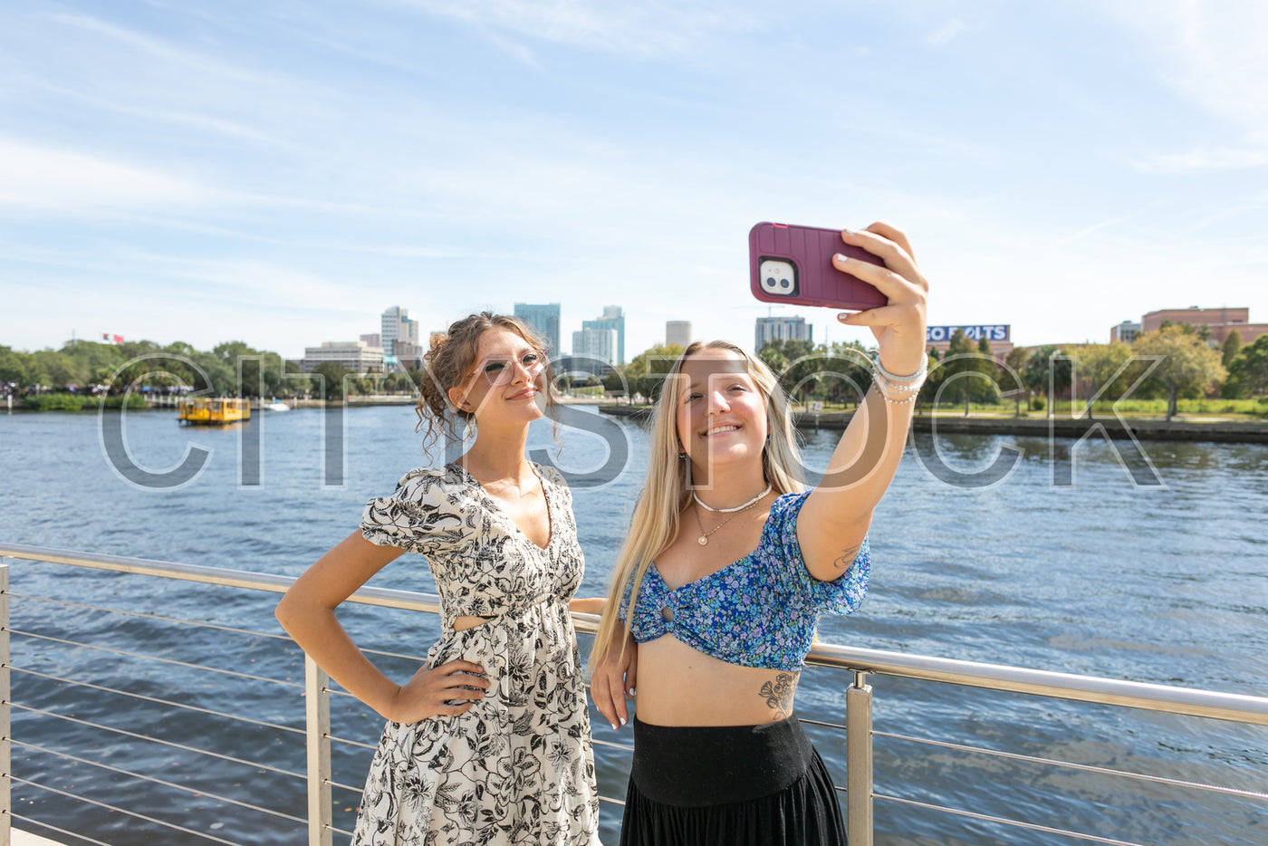Young women taking a selfie on Tampa riverside, sunny city backdrop