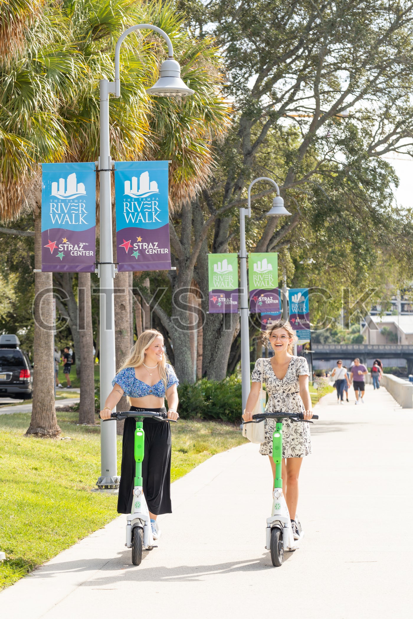 Young women riding electric scooters along Tampa Riverwalk