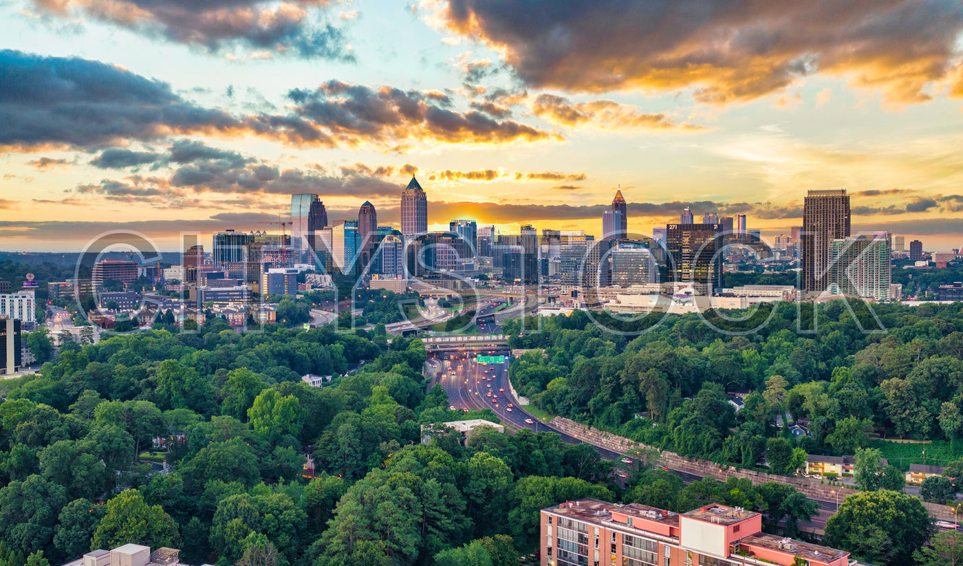 Aerial View of Atlanta Skyline at Sunset with Lush Greenery and Busy Roads
