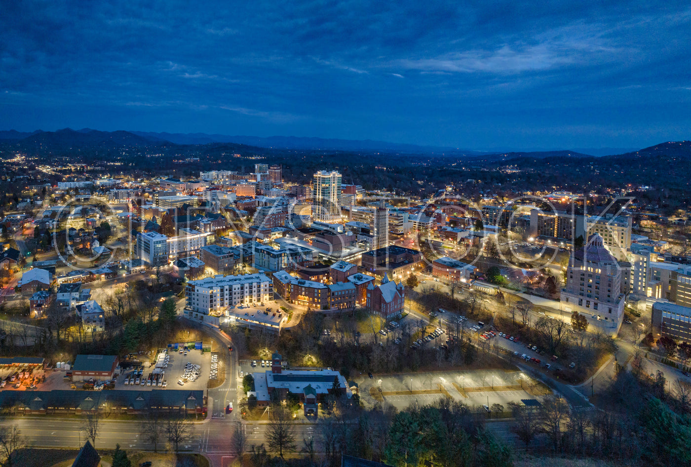 Aerial view of Asheville cityscape at dusk with Blue Ridge Mountains in the background