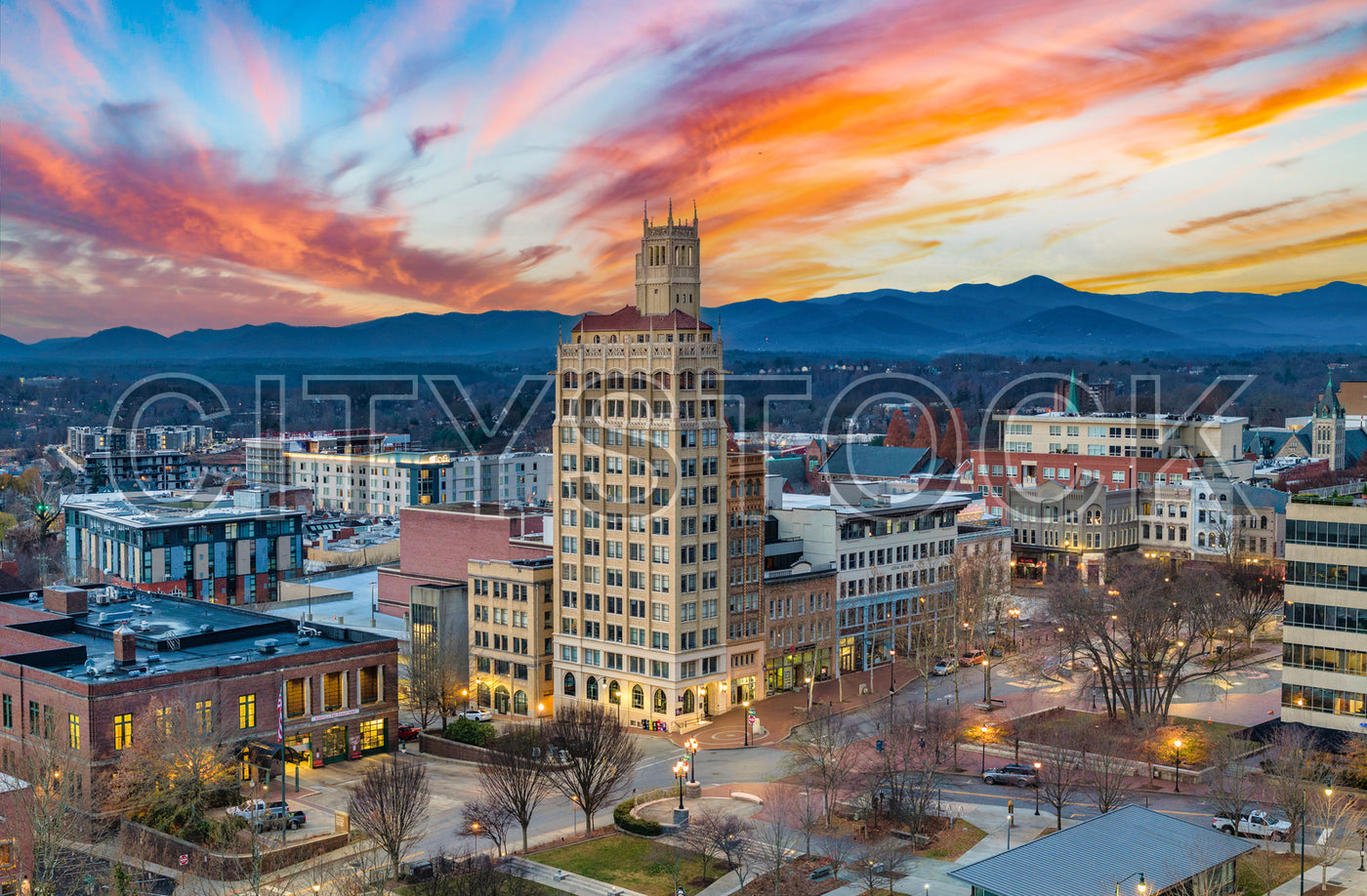 Aerial view of Asheville, NC at sunset with City Hall and mountains