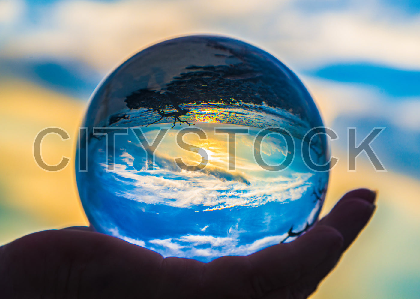 Hand holding glass orb reflecting sunset, Edisto Island