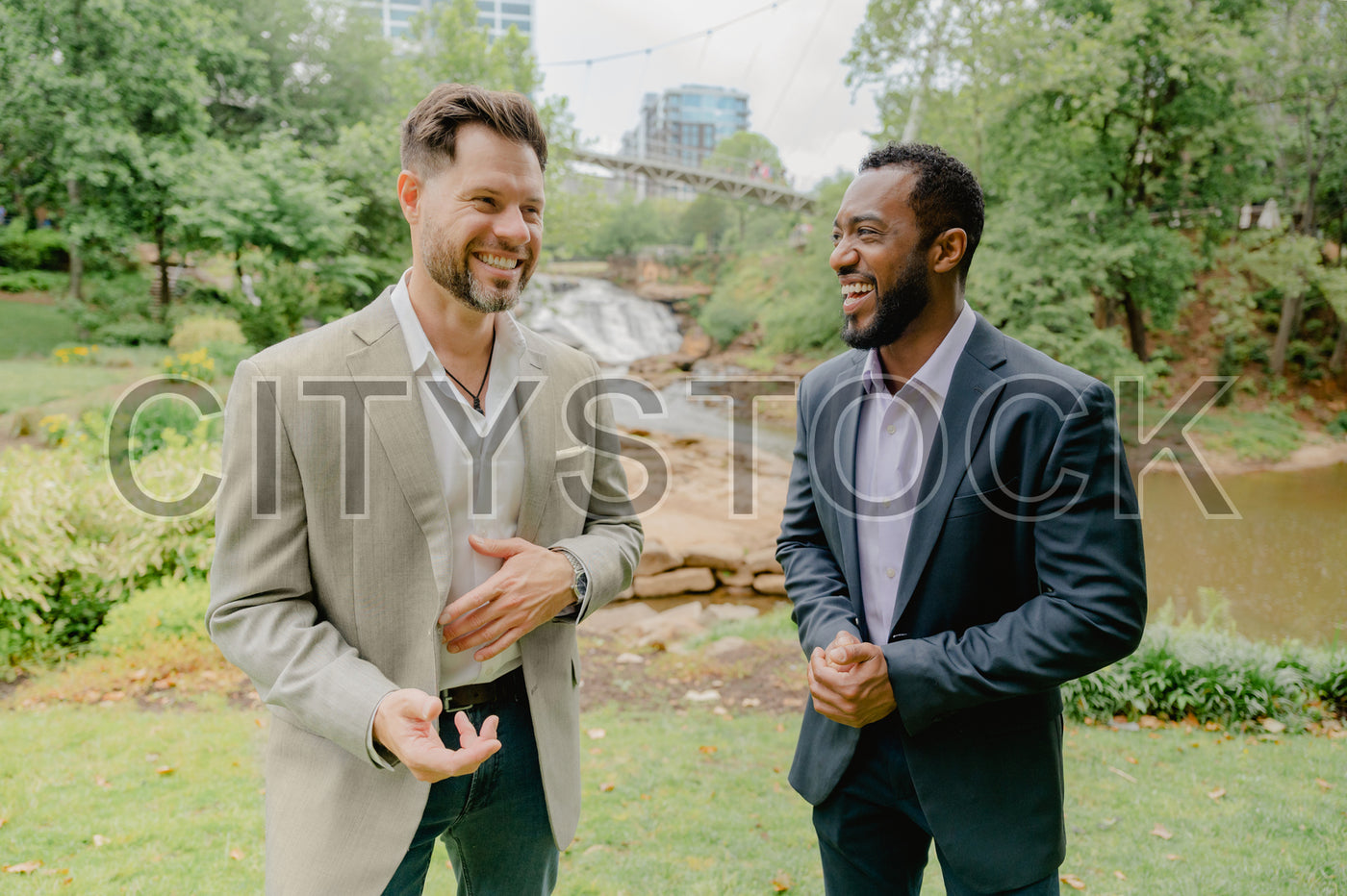 Two professionals laughing in a park meeting, Greenville SC