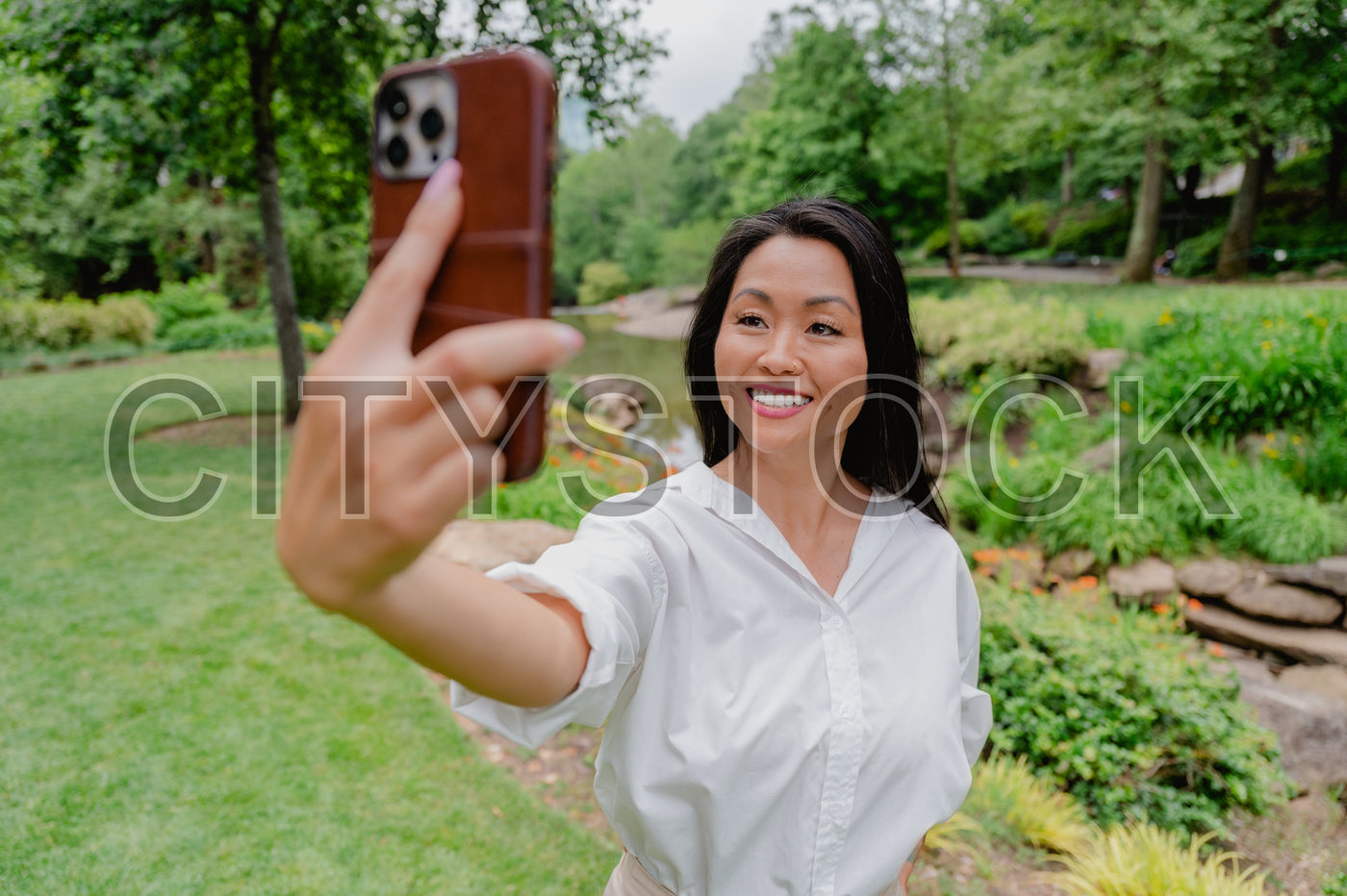 Asian woman in white shirt taking selfie in Greenville park