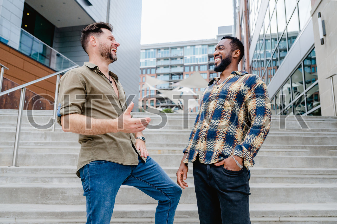 Two young men laughing together on city stairs in Greenville