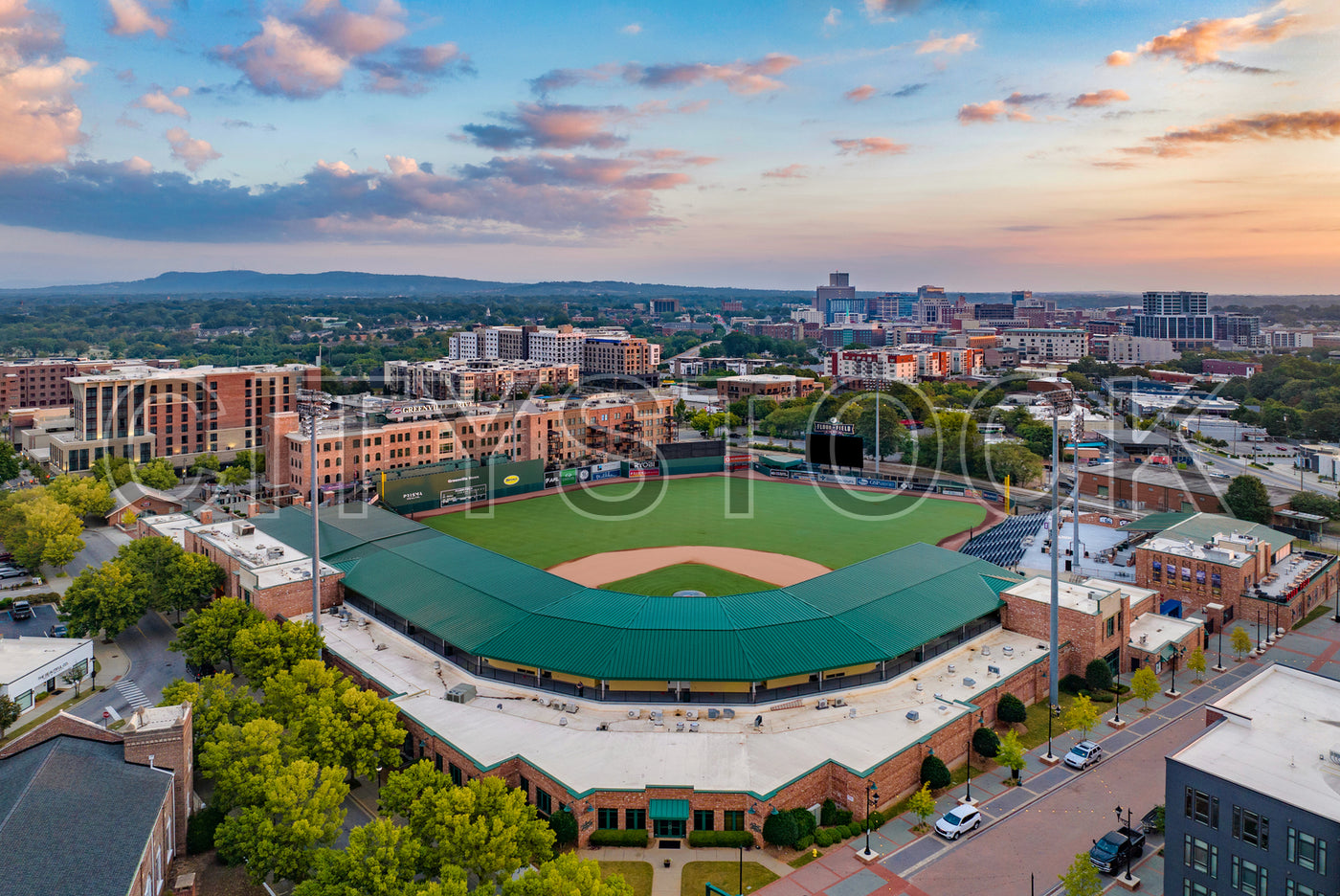 Aerial view of Greenville baseball stadium and city at sunset