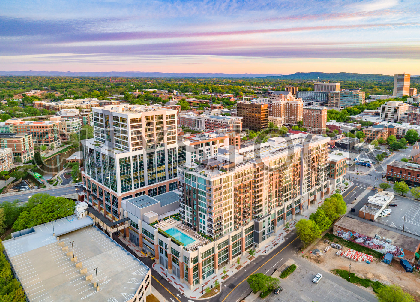 Aerial view of modern Greenville, SC at sunset with mountains