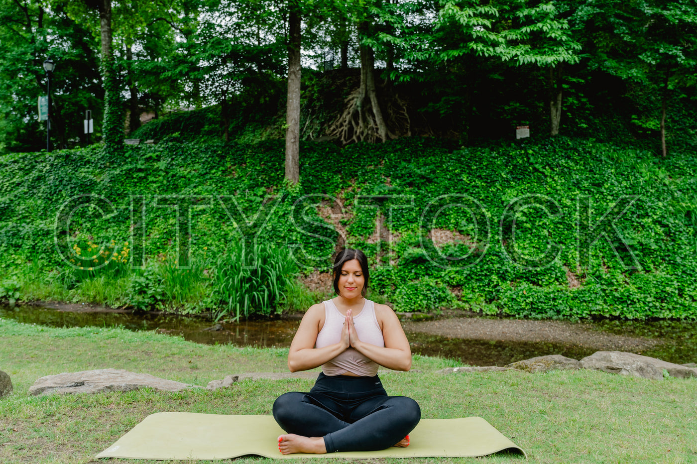 Woman in yoga pose in Greenville park with lush green background
