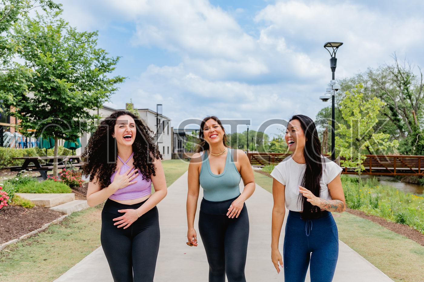 Three joyful women walking in Greenville park, laughing together