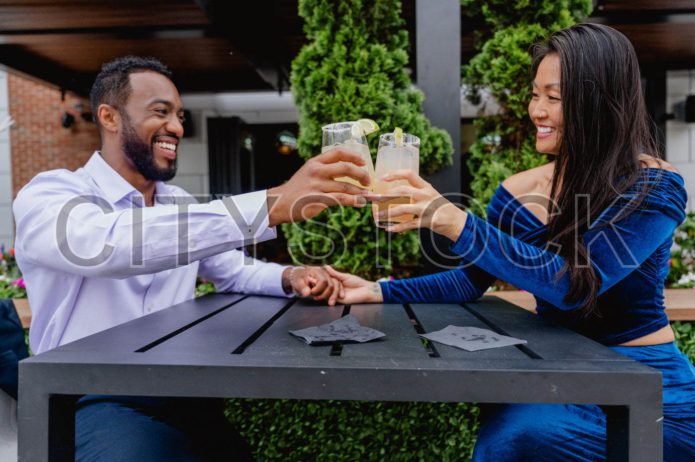 Cheerful couple clinking glasses in Greenville, SC outdoor setting