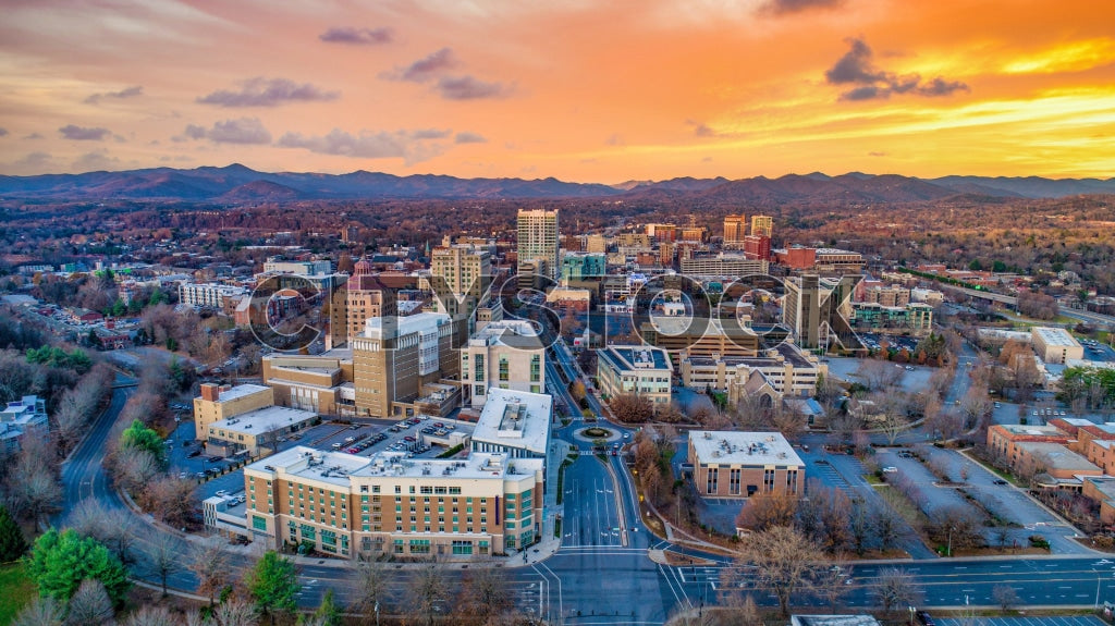 Aerial view of Asheville, NC at sunset with downtown and mountains