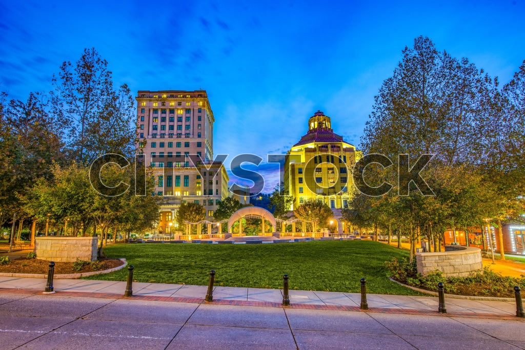 Asheville downtown cityscape at twilight with illuminated buildings and green spaces