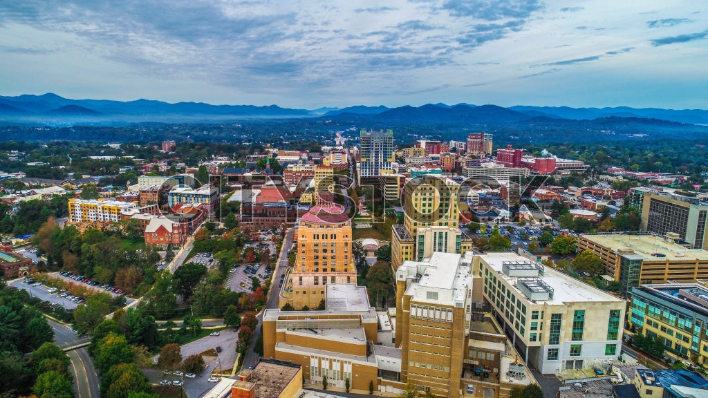 Asheville NC cityscape at dusk with Blue Ridge Mountains background