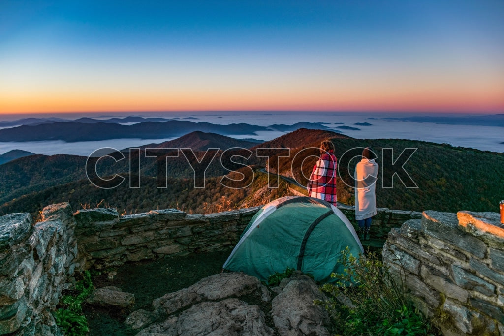 Two campers at dawn overlooking mist-covered mountains in Asheville