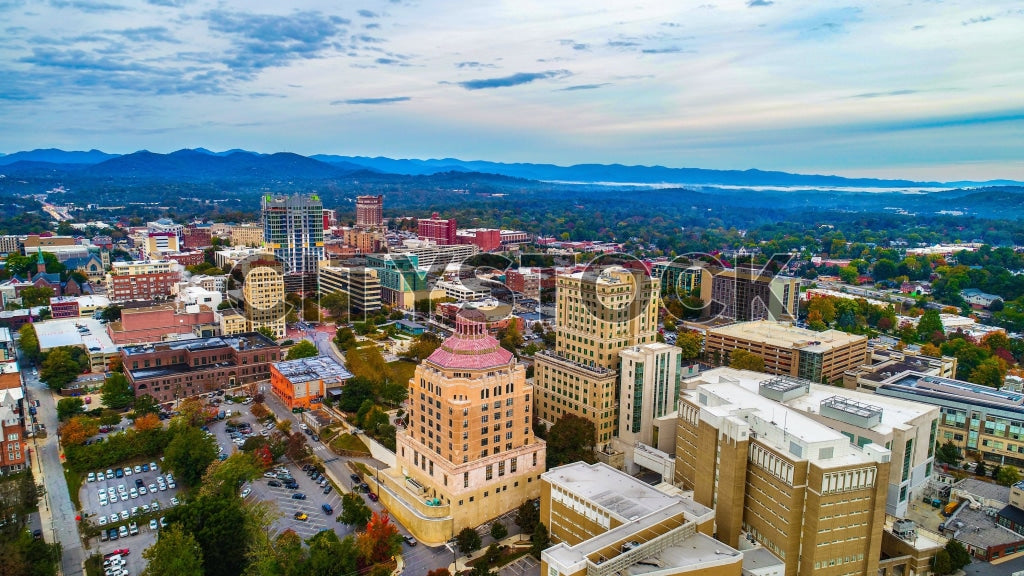 Aerial sunset view of Asheville, NC showing cityscape and mountains