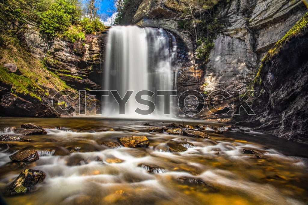 Majestic waterfall in Asheville under blue sky with lush forest