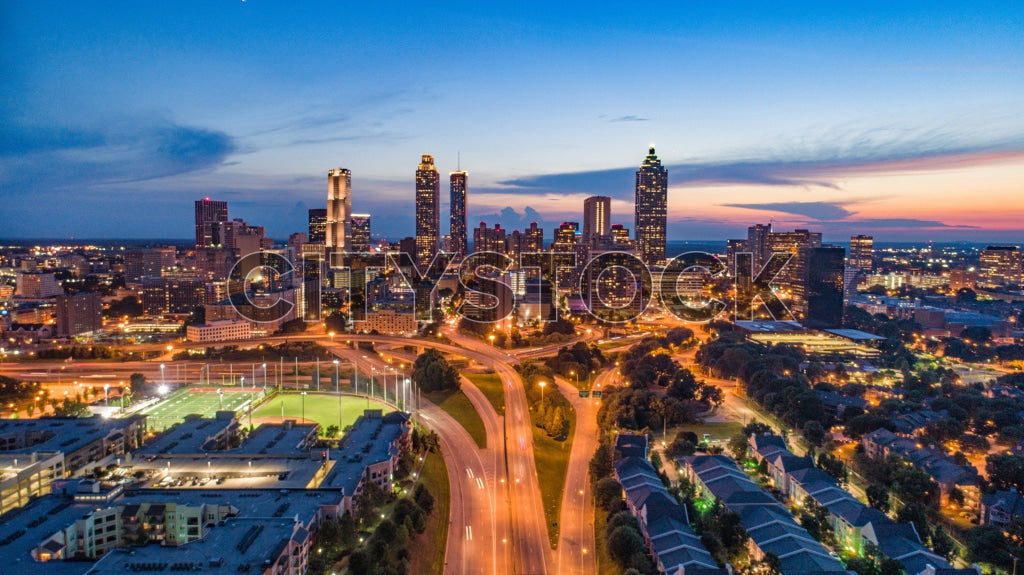 A panoramic view of Atlanta skyline at twilight with skyscrapers and a lit baseball diamond