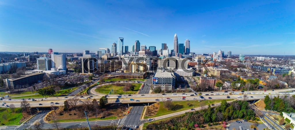 Aerial view of Charlotte, NC skyline with highways under blue skies