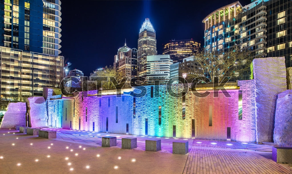 Colorful illuminated stone columns at night in Charlotte, surrounded by modern skyscrapers