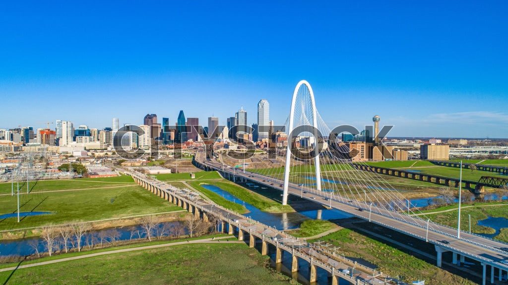 Aerial view of Dallas skyline with Margaret Hunt Hill Bridge under blue sky