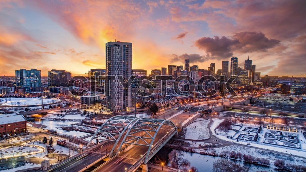 Aerial view of Denver skyline at sunset with snow-covered river