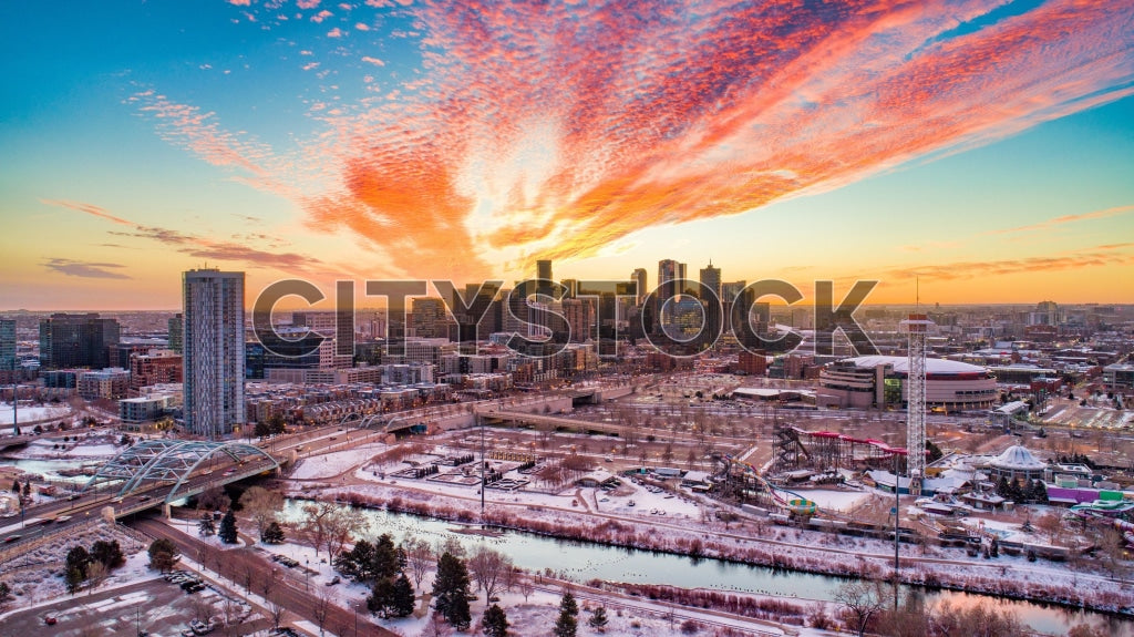 Aerial view of Denver skyline during sunrise with colorful clouds and snow