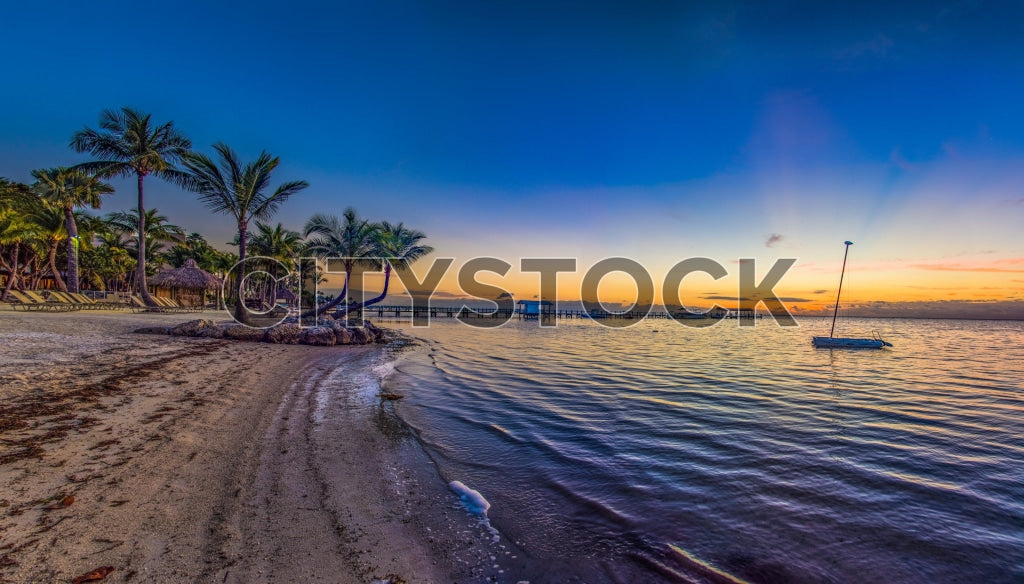 Sunset view with sailboat and palm trees at Florida Keys beach