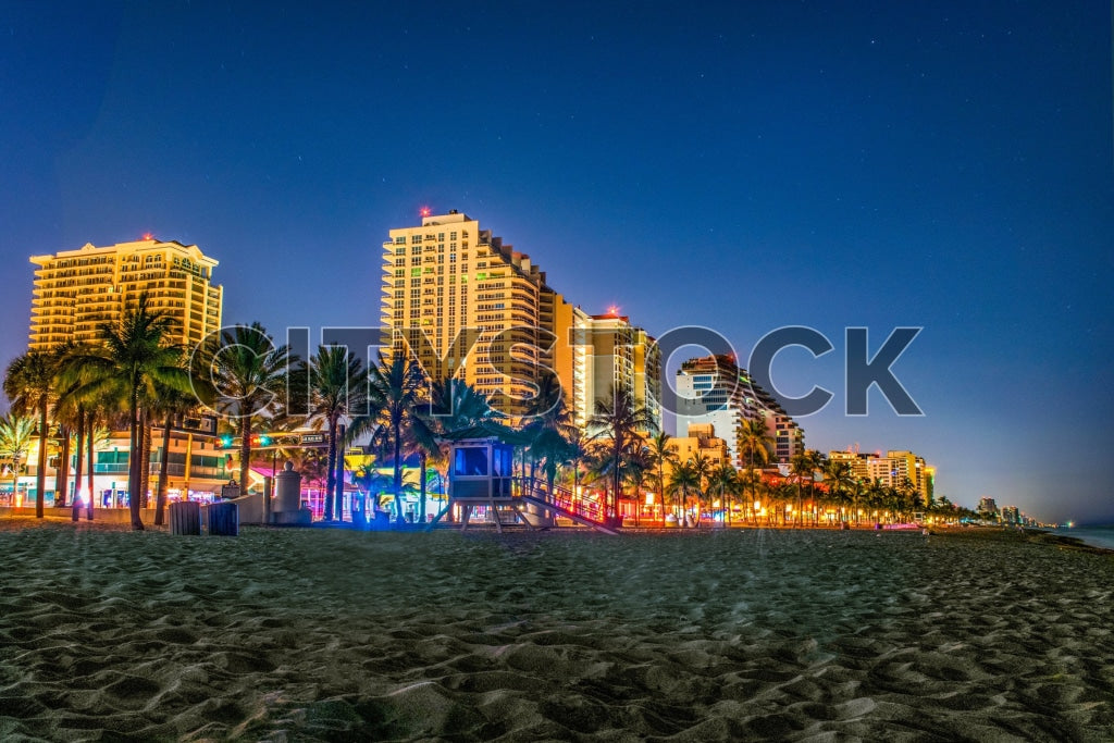 Twilight scene of Fort Lauderdale beachfront with lit-up palm trees and condos