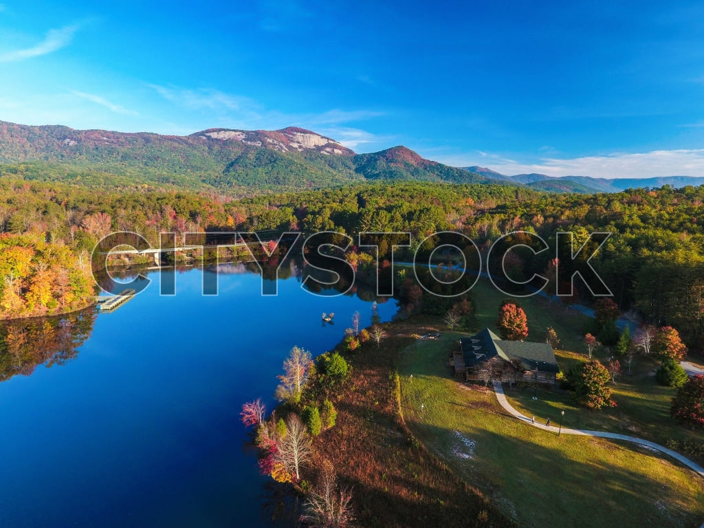 Aerial view of a lake and cabin with autumn mountains in Greenville, SC