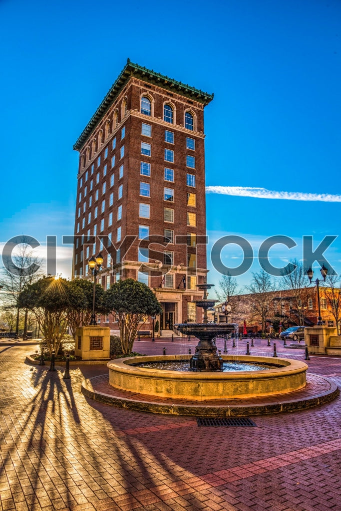 Golden hour view of a historic building and fountain in Greenville