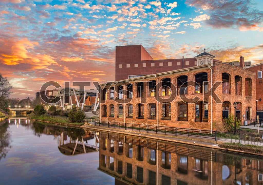 Sunset over historical Greenville, SC riverfront with building reflections