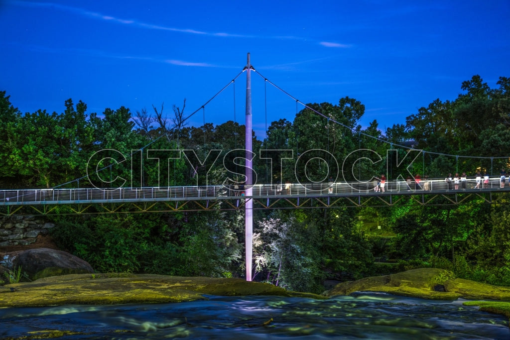 Twilight view of suspension bridge over river in Greenville, SC