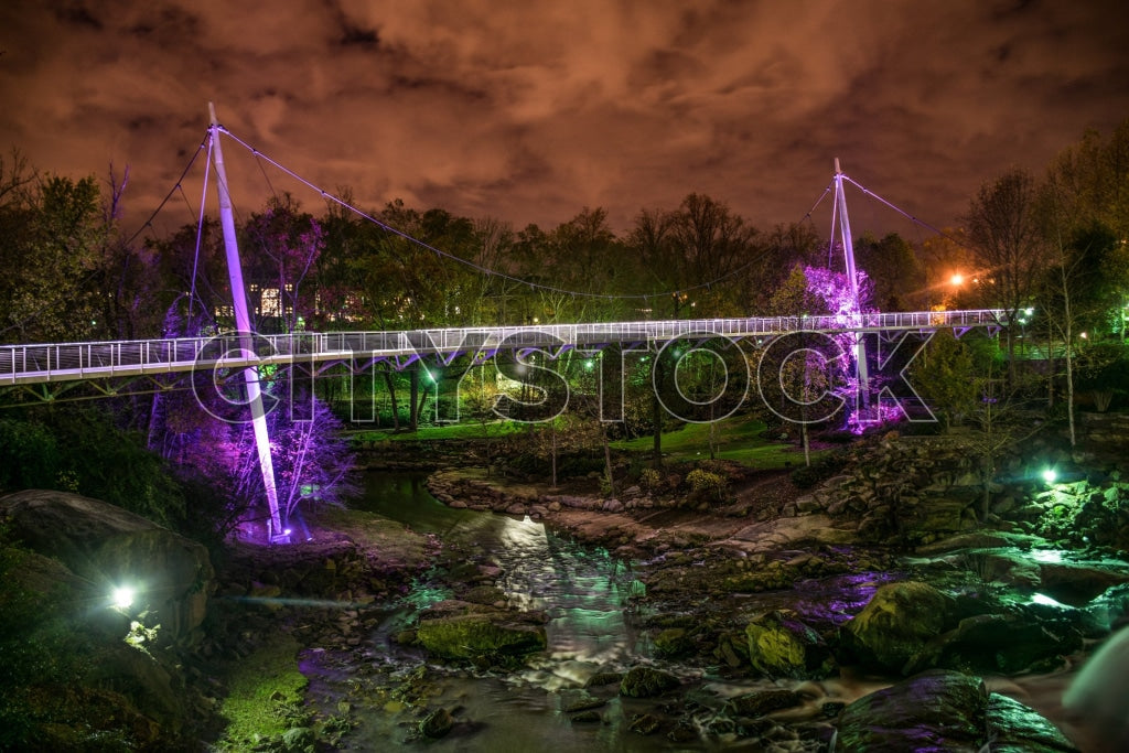Greenville bridge under purple lighting at twilight with urban backdrop