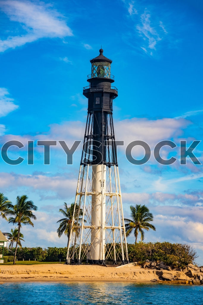 Hillsboro Beach lighthouse against blue sky with palm trees