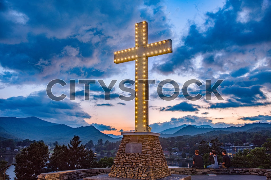 Illuminated Christian cross at sunset in Lake Junaluska, NC with mountain backdrop