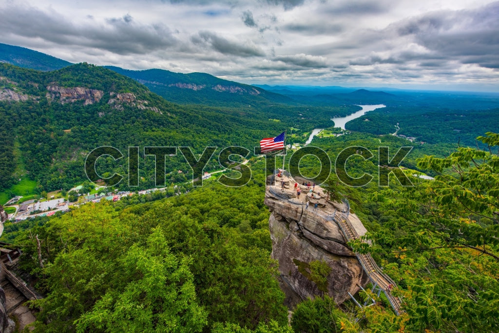 American flag waving on Chimney Rock with Lake Lure and mountains