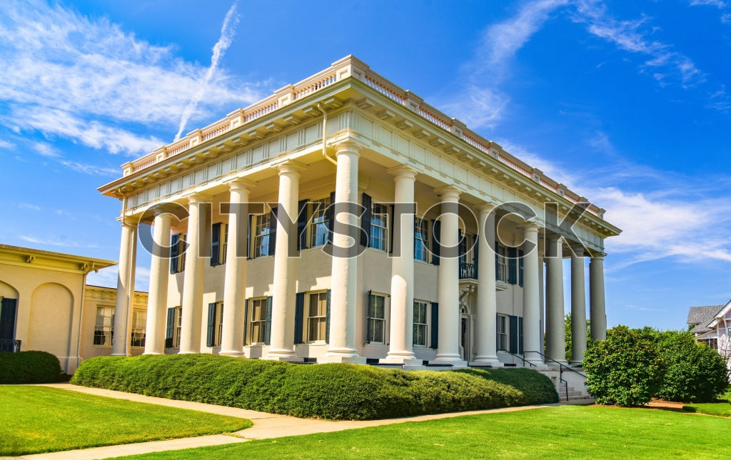 Majestic neoclassical mansion in Macon, Georgia, with green lawn and blue sky