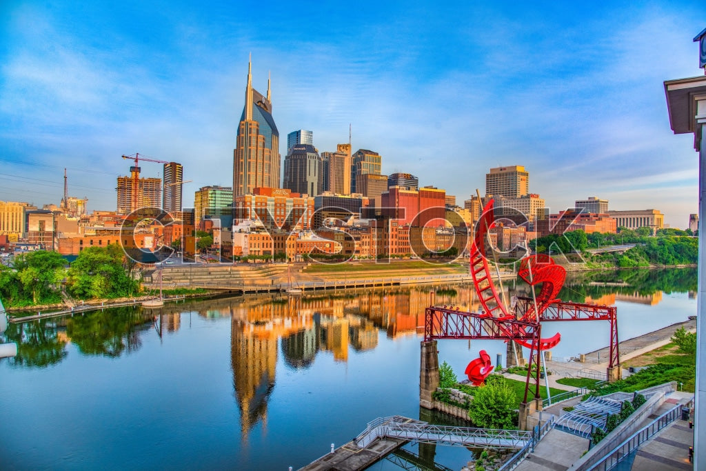 Nashville cityscape at sunrise, reflecting river and blue sky