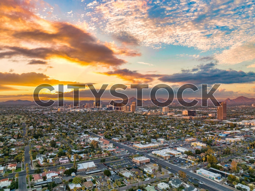 Aerial view of Phoenix, Arizona cityscape with colorful sunrise and mountains in the backdrop